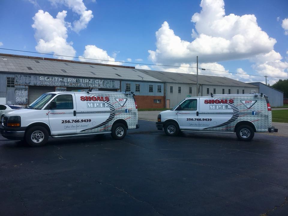 Two white vans are parked next to each other in front of a building.