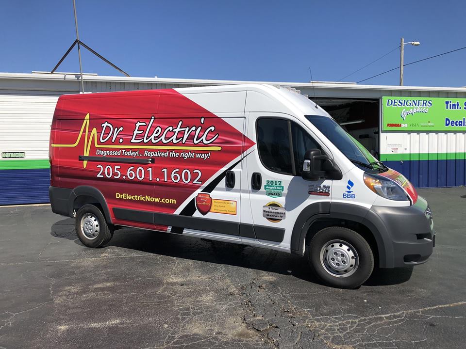 A dr. electric van is parked in front of a building