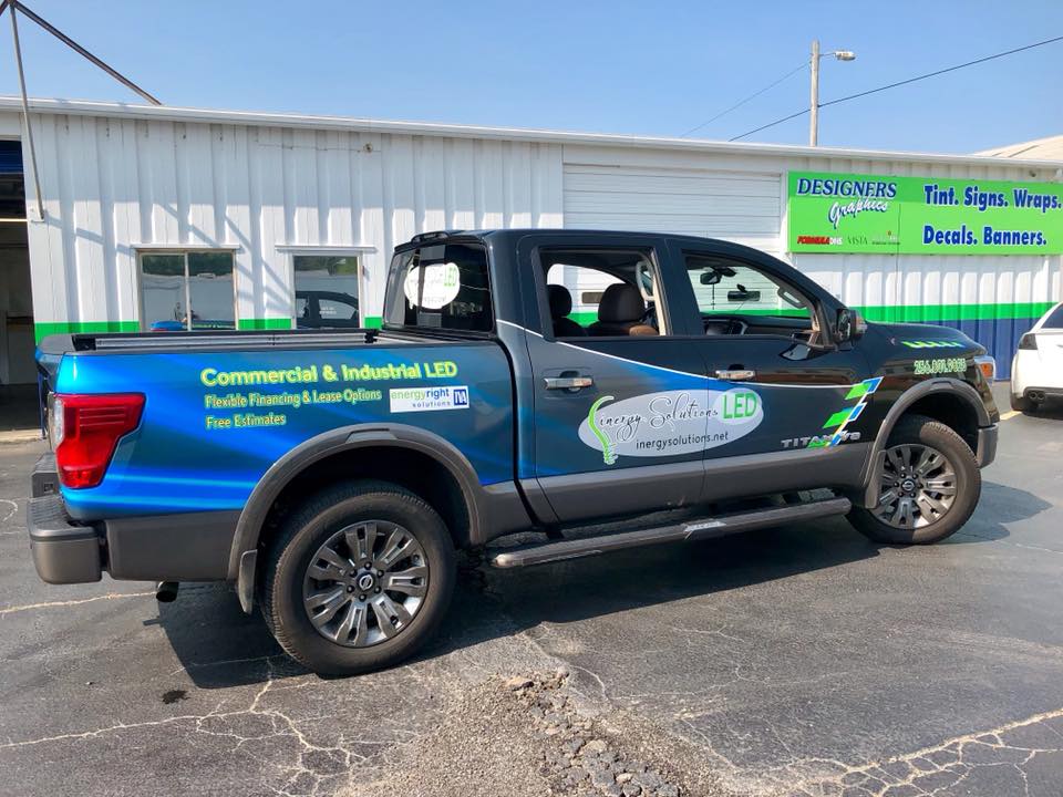 A blue and black truck is parked in front of a building.