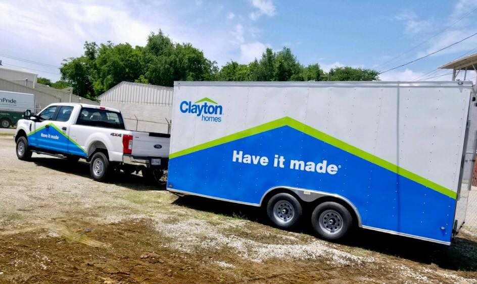 Two trucks are towing a trailer that says