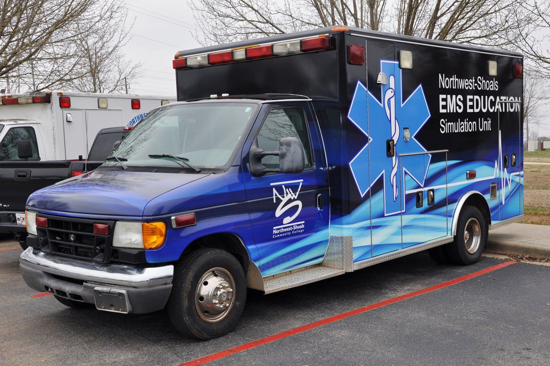 A blue and black ambulance is parked in a parking lot