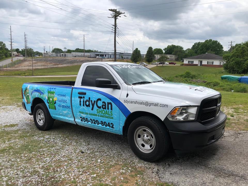 A white and blue truck is parked in a grassy field.