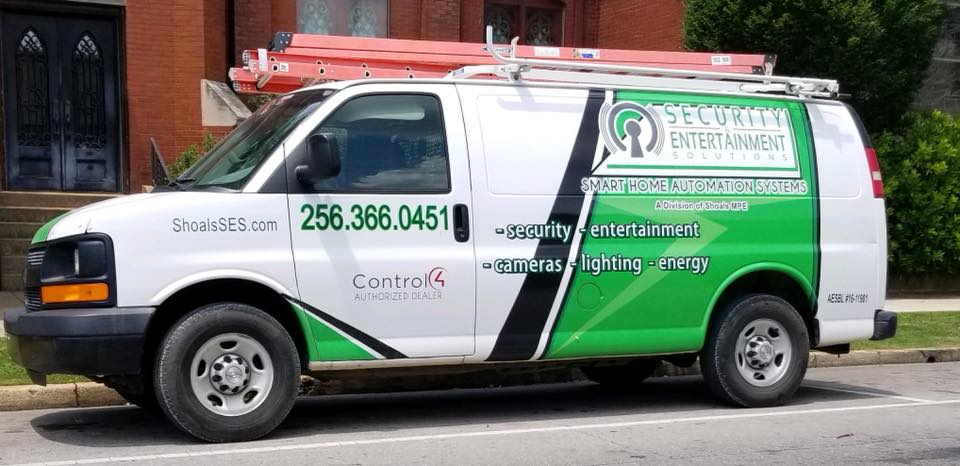 A green and white van is parked on the side of the road