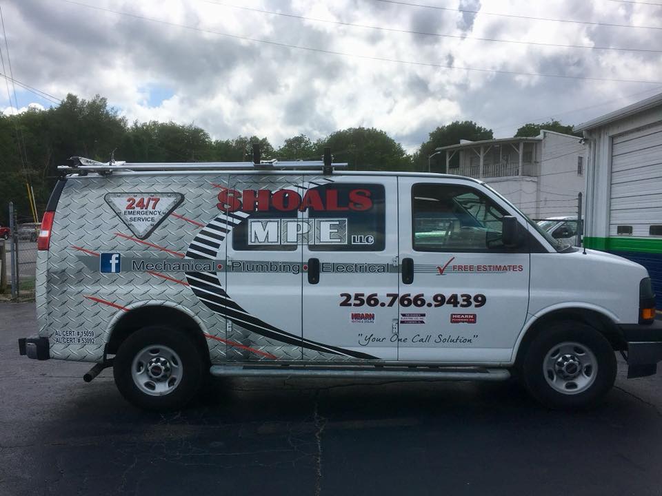A white van is parked in front of a garage.