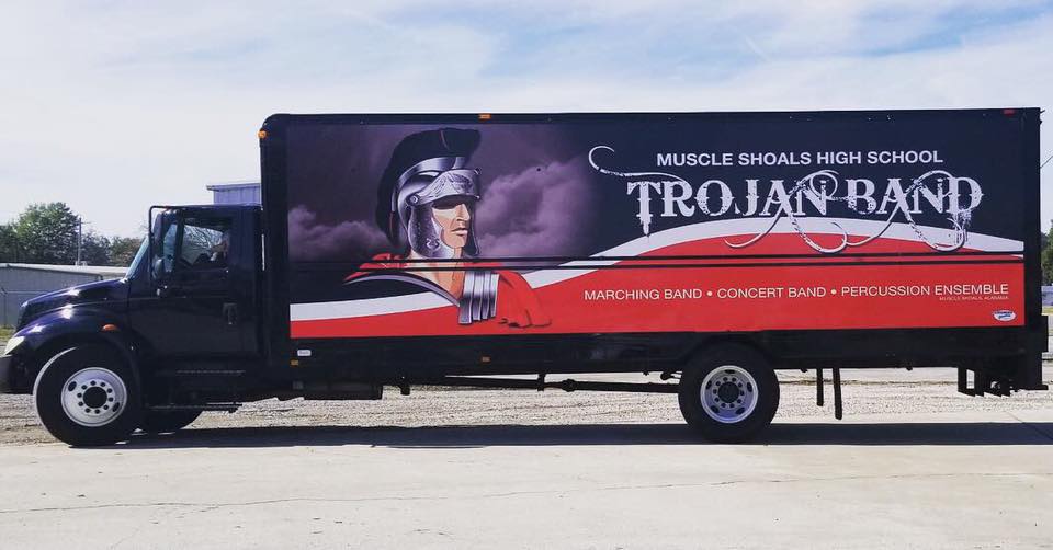 A trojan band truck is parked in a parking lot.