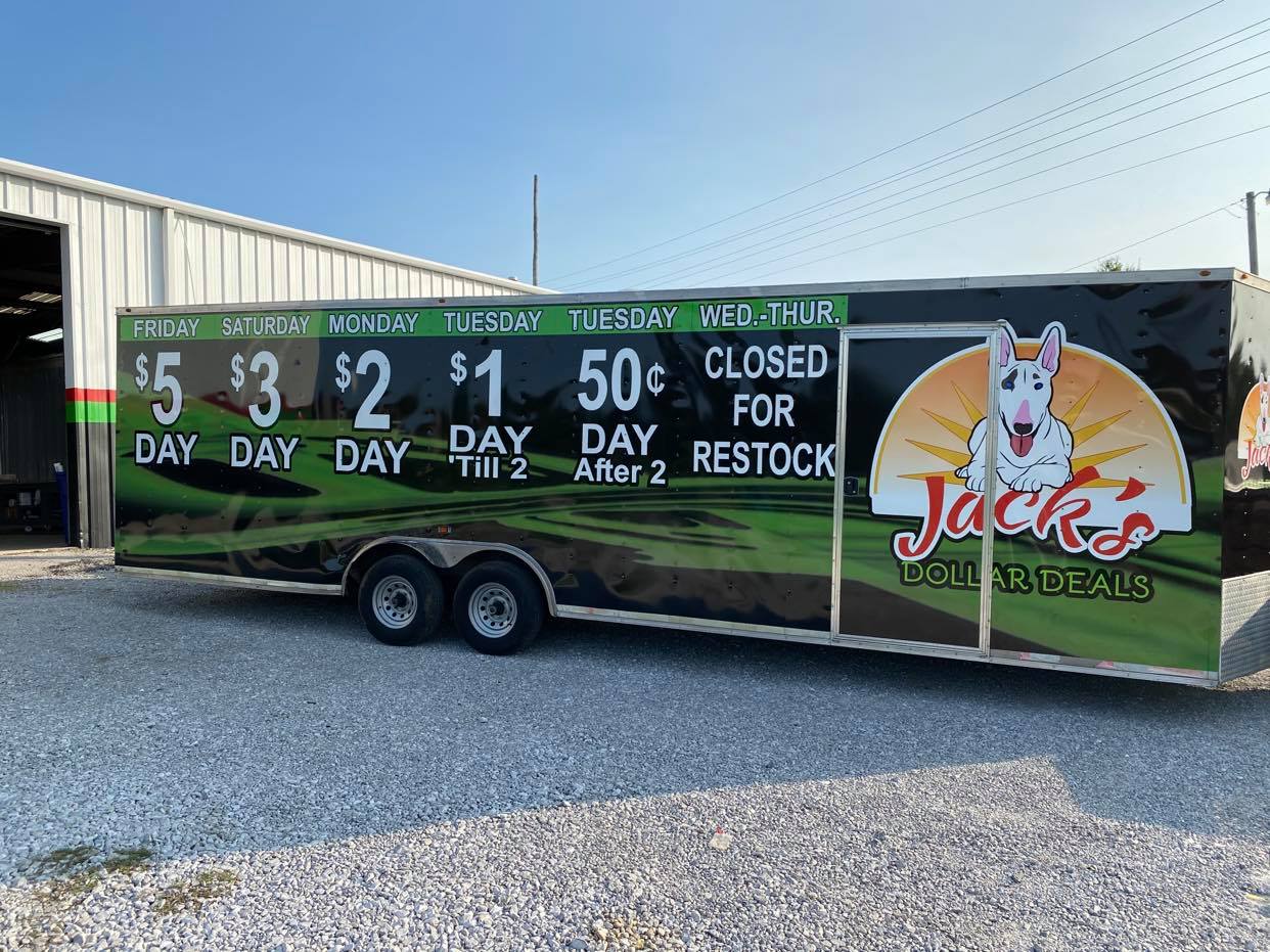 A trailer with a dog on it is parked in front of a building.