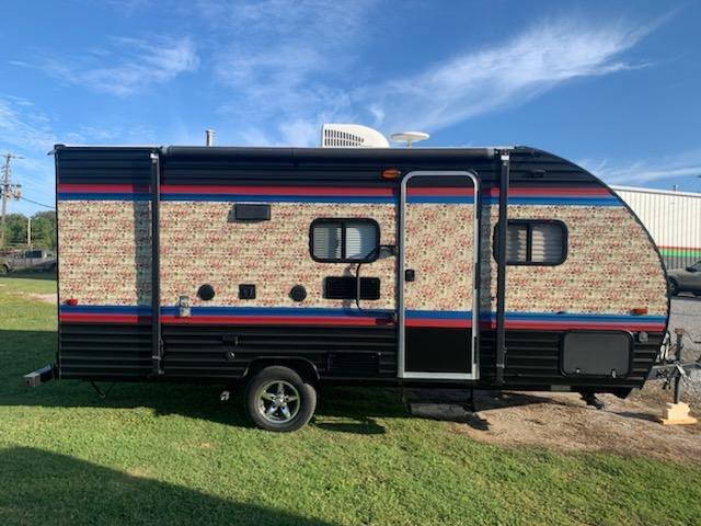 A small trailer is parked in a grassy field.