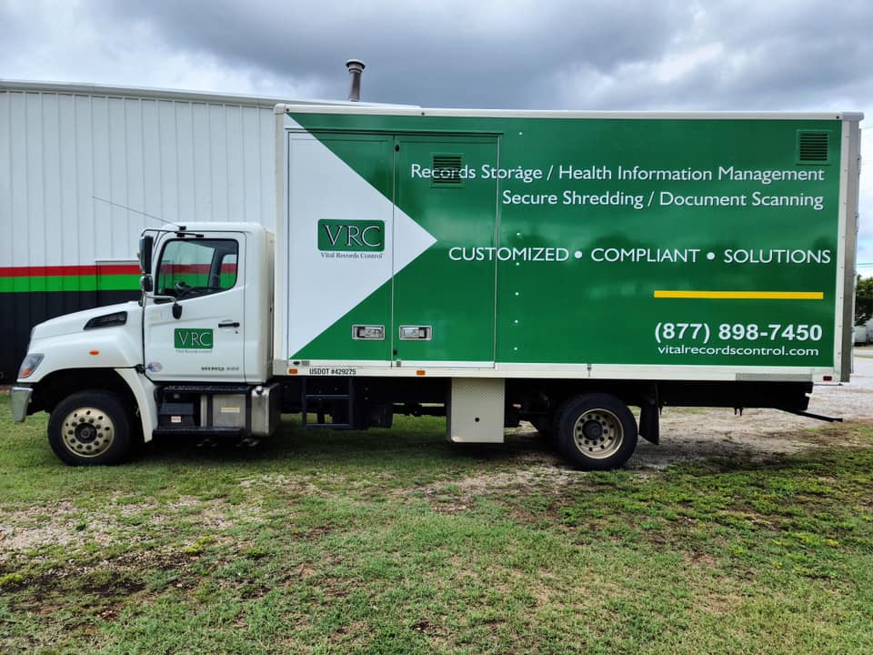A green and white truck is parked in front of a building.