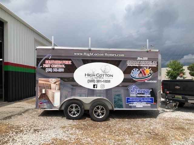 A trailer for high cotton is parked in a gravel lot