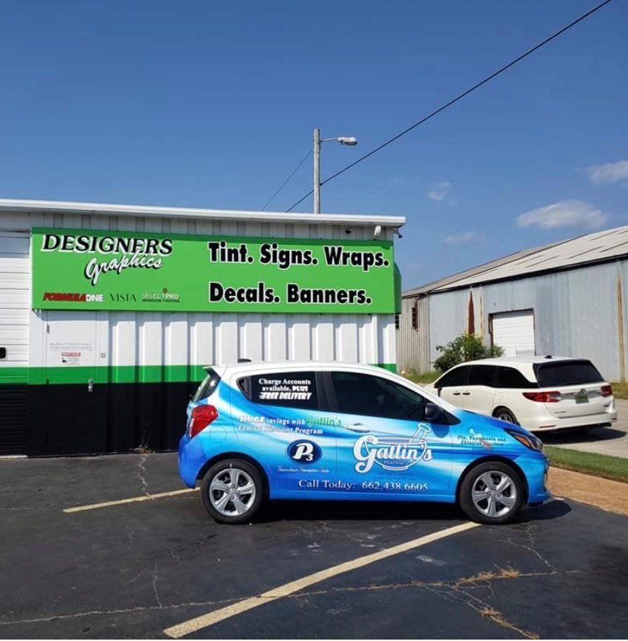 A car is parked in front of a building that says designers graphics
