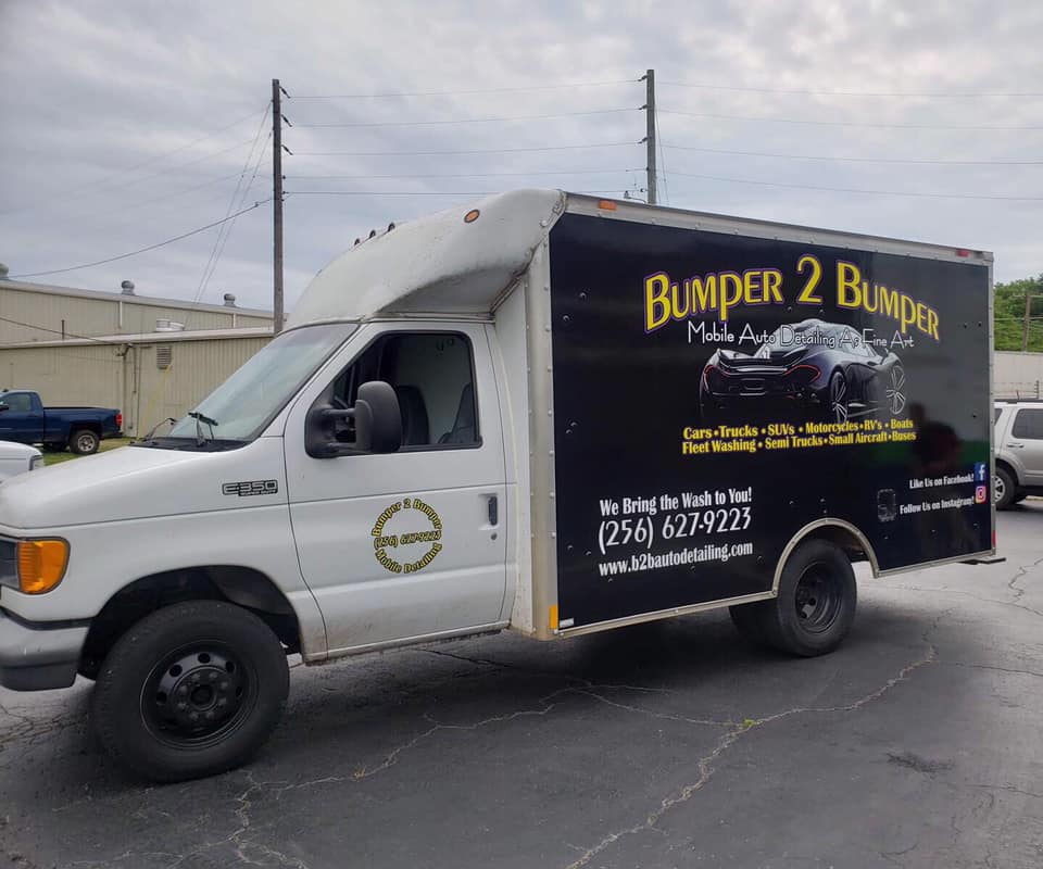 A bumper 2 bumper truck is parked in a parking lot