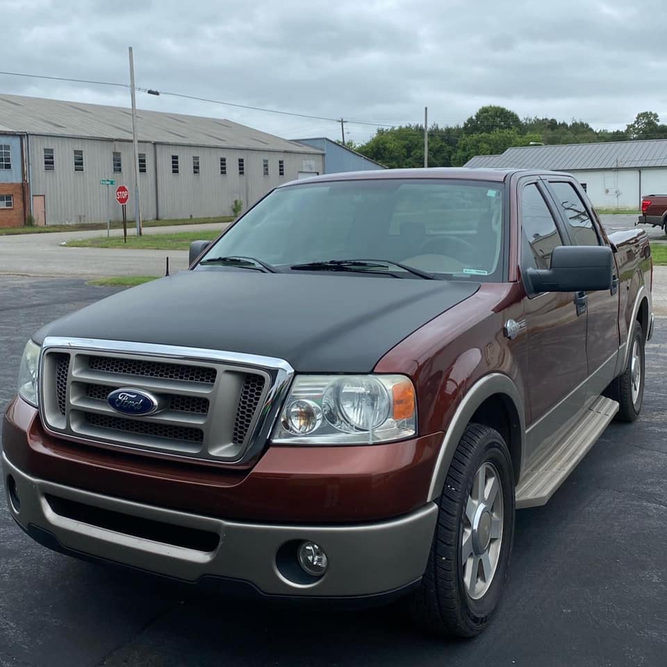 A brown ford truck is parked in a parking lot