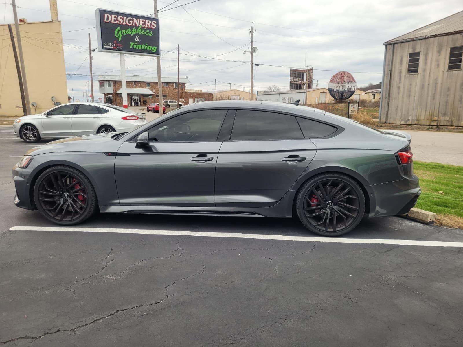 a gray car is parked in a parking lot in front of a building