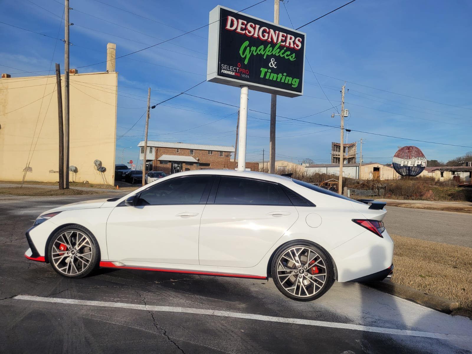 a white car is parked in front of a sign for designers graphics and tinting