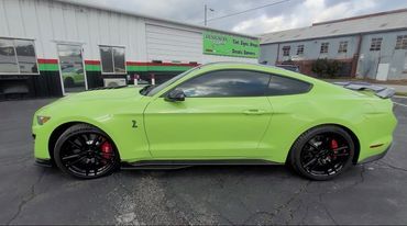 A green ford mustang is parked in front of a building.