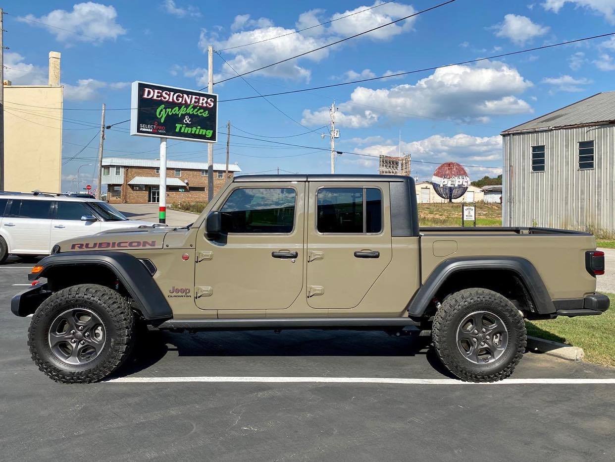 A jeep gladiator pickup truck is parked in a parking lot in front of a building.