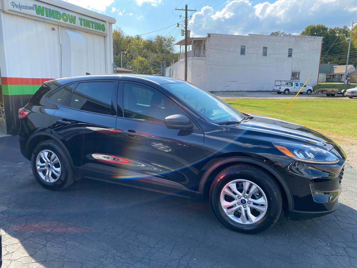 A black ford escape is parked in front of a building.