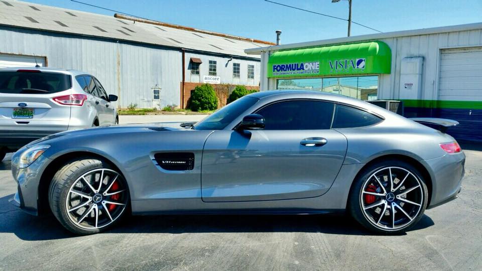 A silver sports car is parked in a parking lot in front of a building.