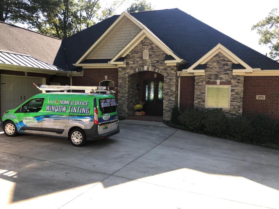 A green van is parked in front of a brick house.