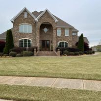 A large brick house with a lush green lawn in front of it.