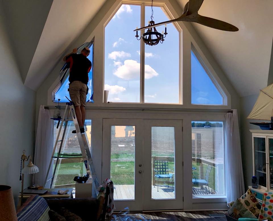 A man on a ladder cleaning a window in a living room