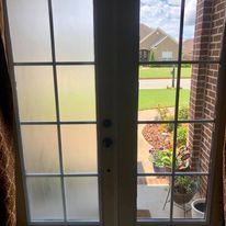 A pair of french doors with frosted glass and a view of a brick building.