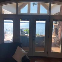 A living room with a couch, fireplace, and sliding glass doors leading to a balcony overlooking the water.