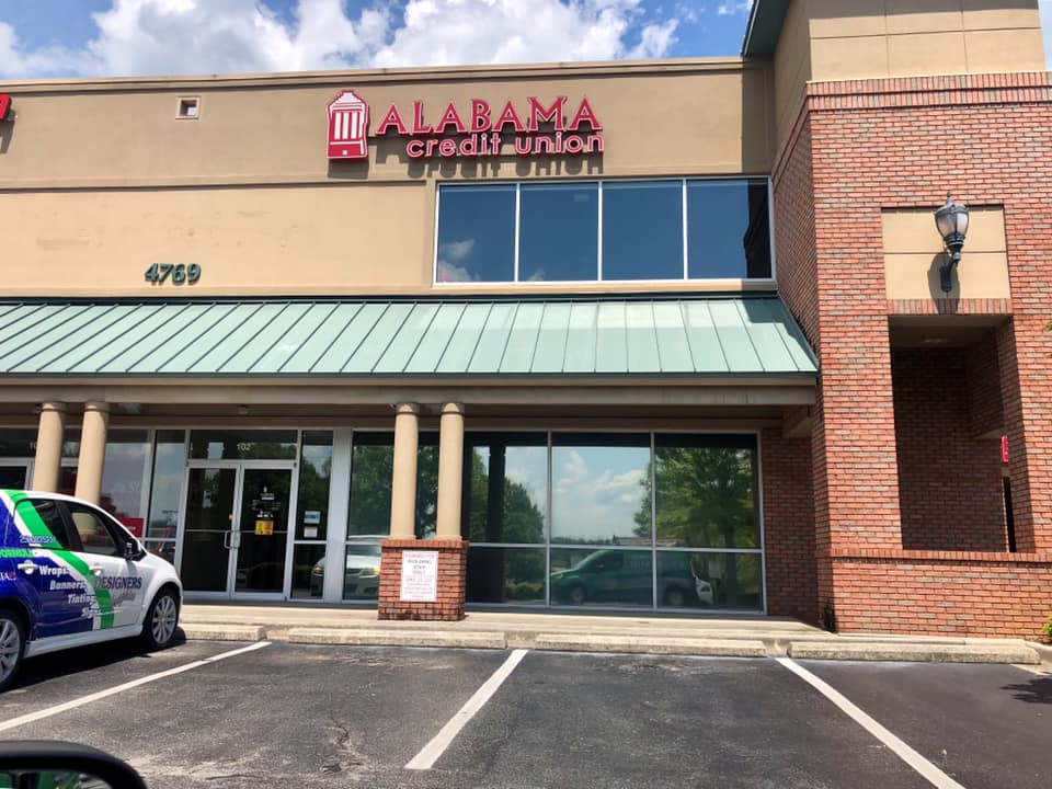 A car is parked in front of a building that says alabama credit union