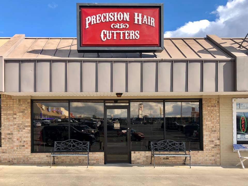 A brick building with a sign that says precision hair cutters