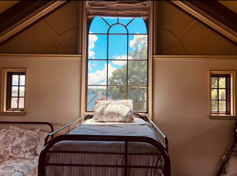 A bedroom with a bed and a window with a view of the sky