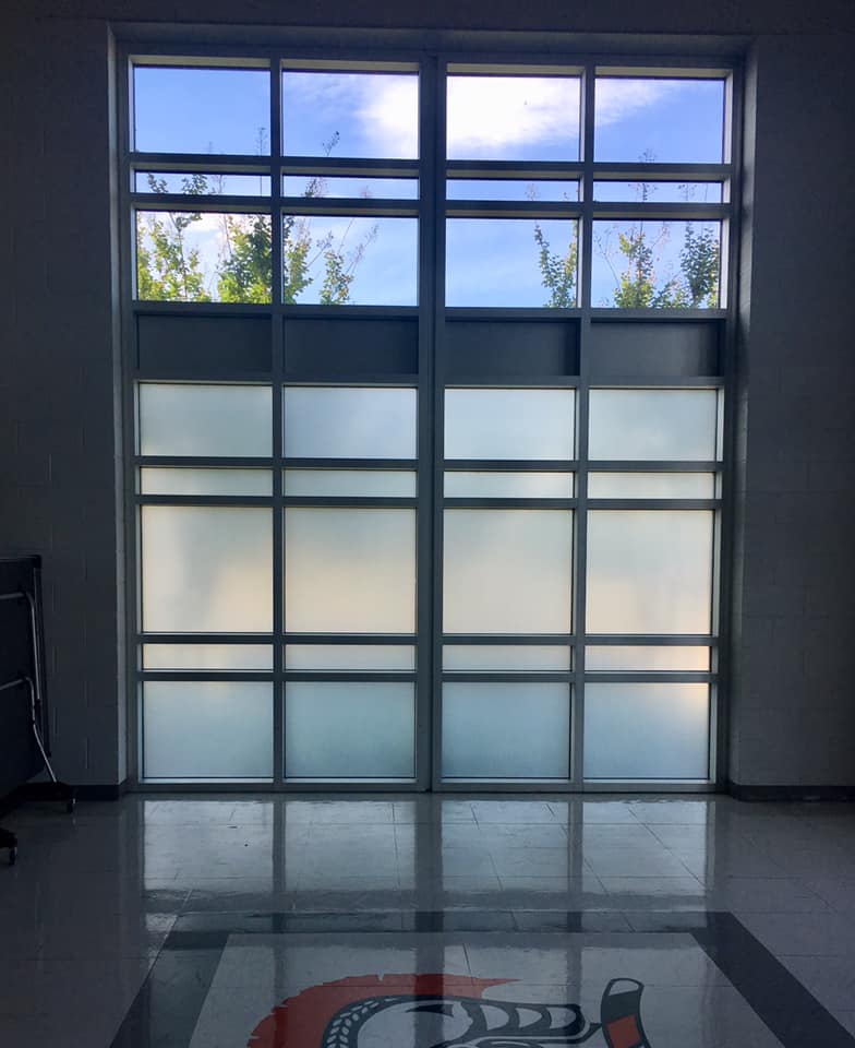 A room with a large window and a logo on the floor