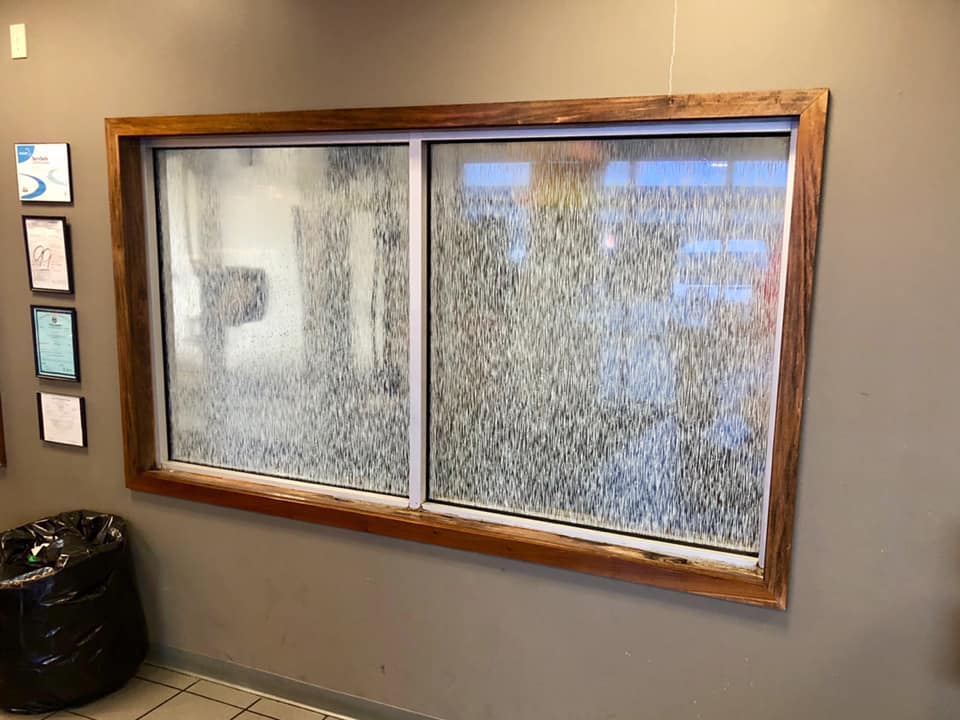 A large window with a wooden frame is hanging on a wall.