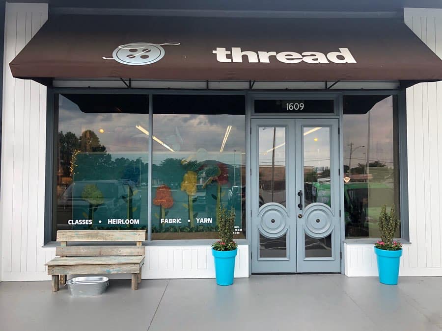 A store front with a brown awning that says thread