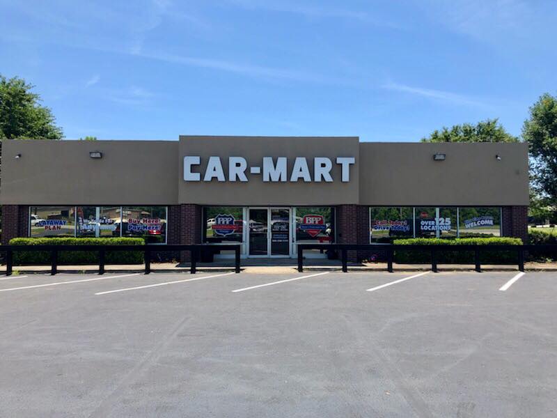 A car mart store with a parking lot in front of it