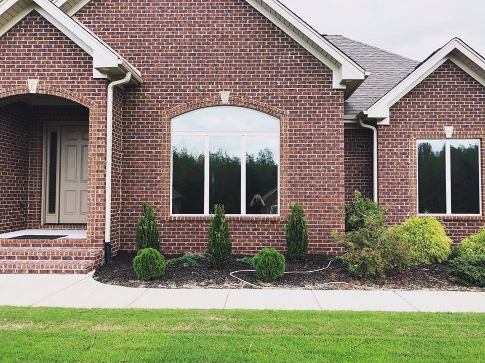 A brick house with a lot of windows and a lush green lawn in front of it.