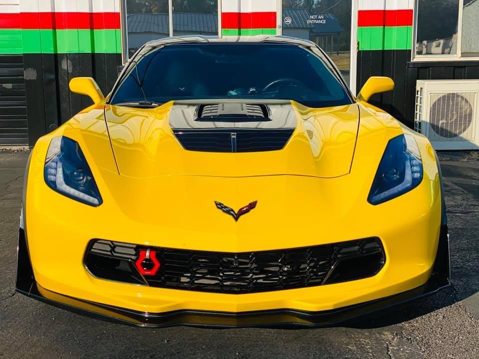 A yellow corvette is parked in front of a building.