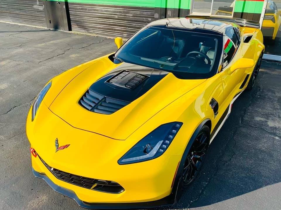 A yellow corvette is parked in a parking lot.