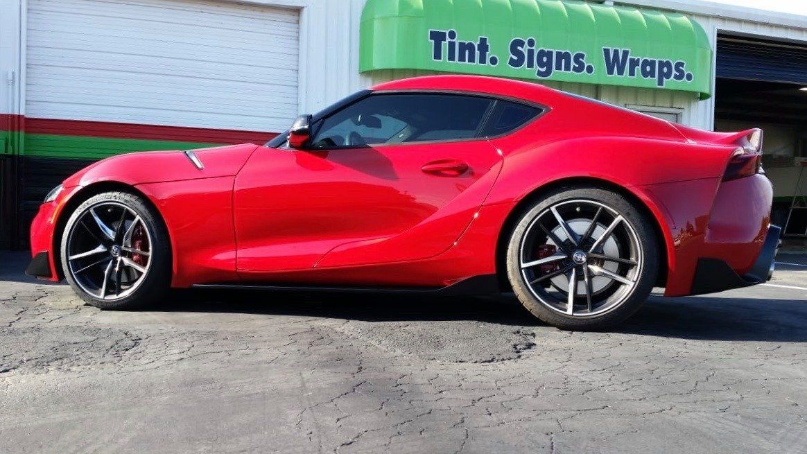 A red sports car is parked in front of a garage.