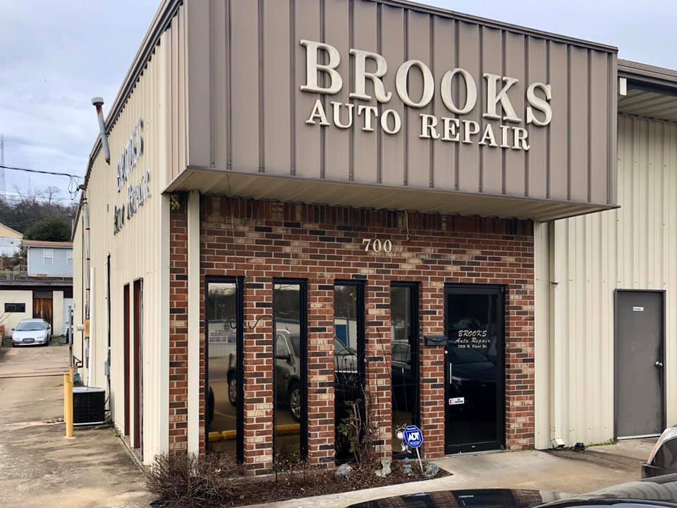 A car is parked in front of a brick building that says brooks auto repair.