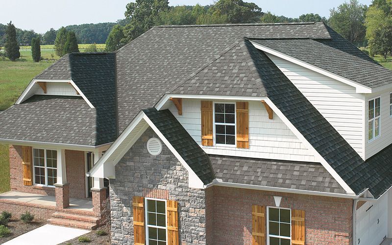 House with a gray shingle roof, brick and white siding, and wooden shutters.