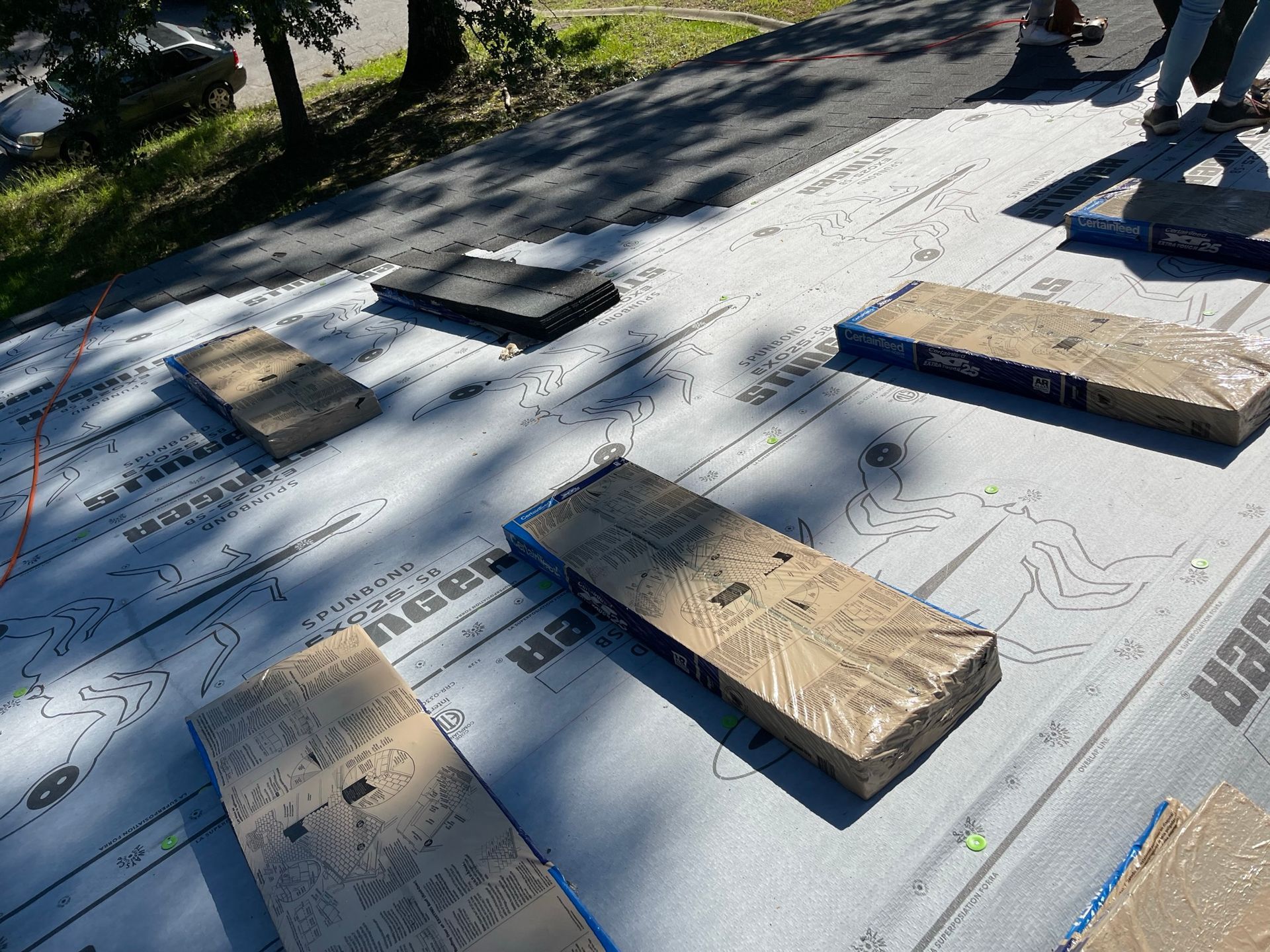 Roof covered in protective underlayment, with bundles of roofing shingles staged for installation.