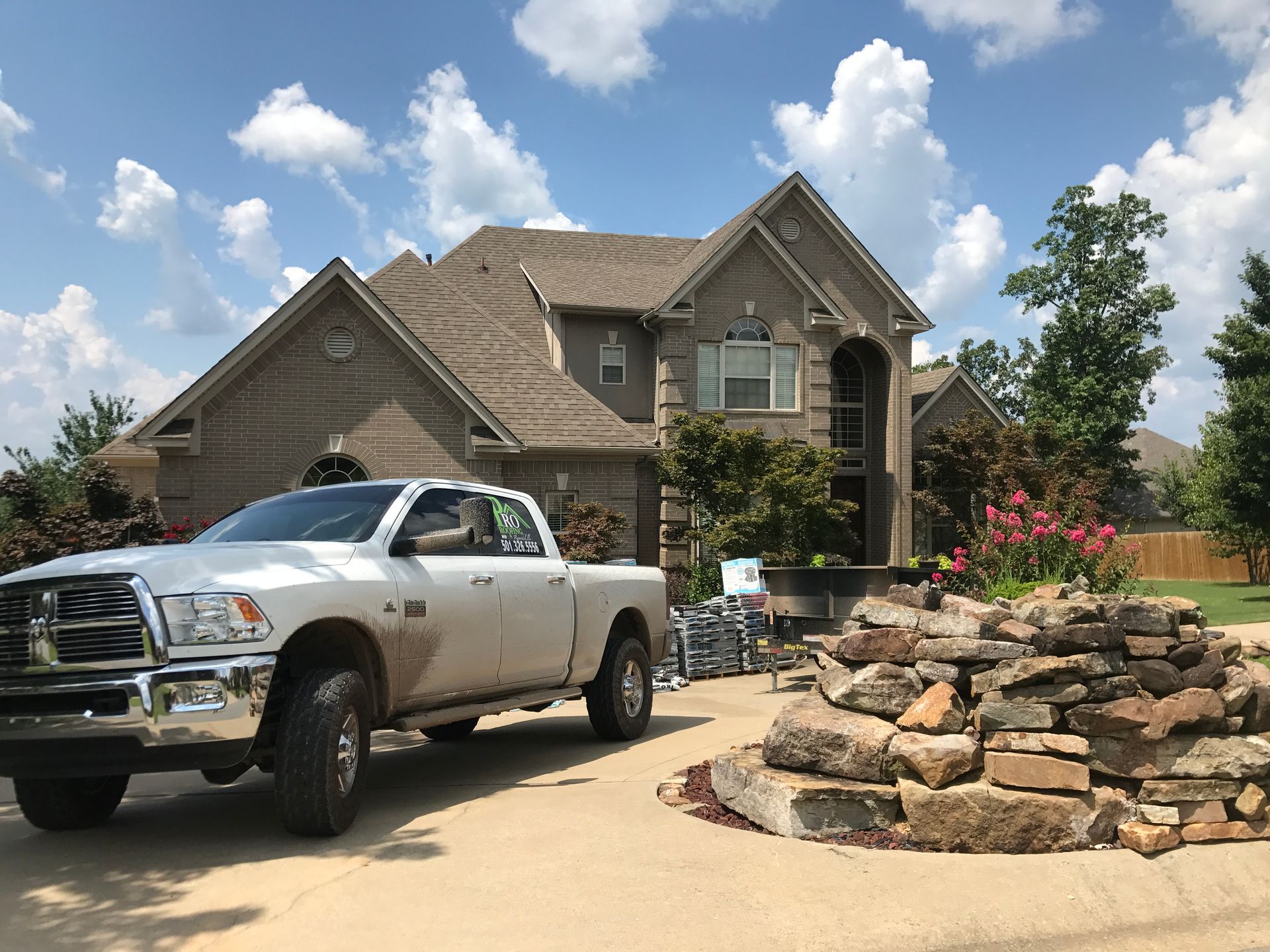 Silver pickup truck parked in front of a two-story brick house with a stone garden.