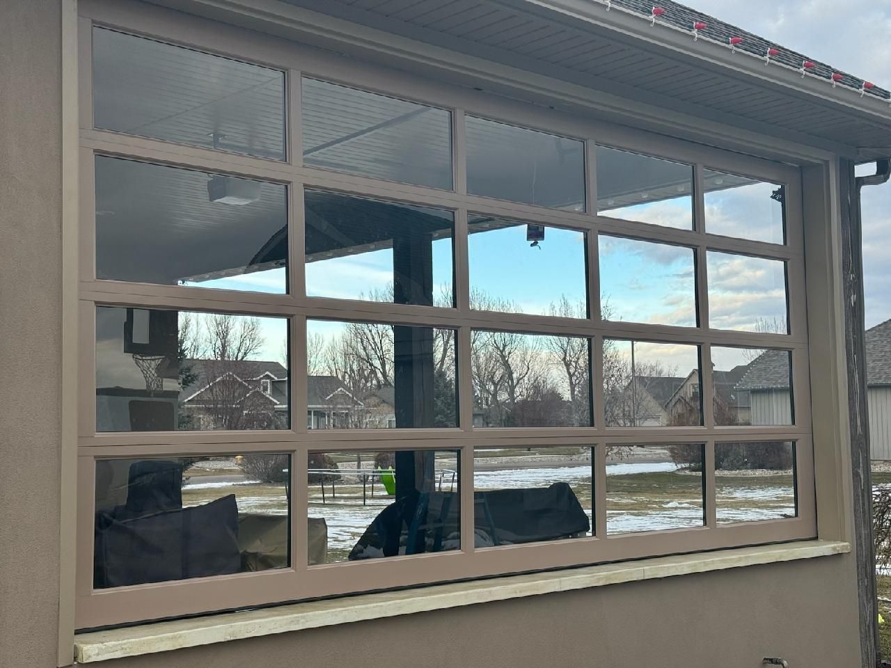 Glass paneled wall with brown frame overlooking a snowy yard.