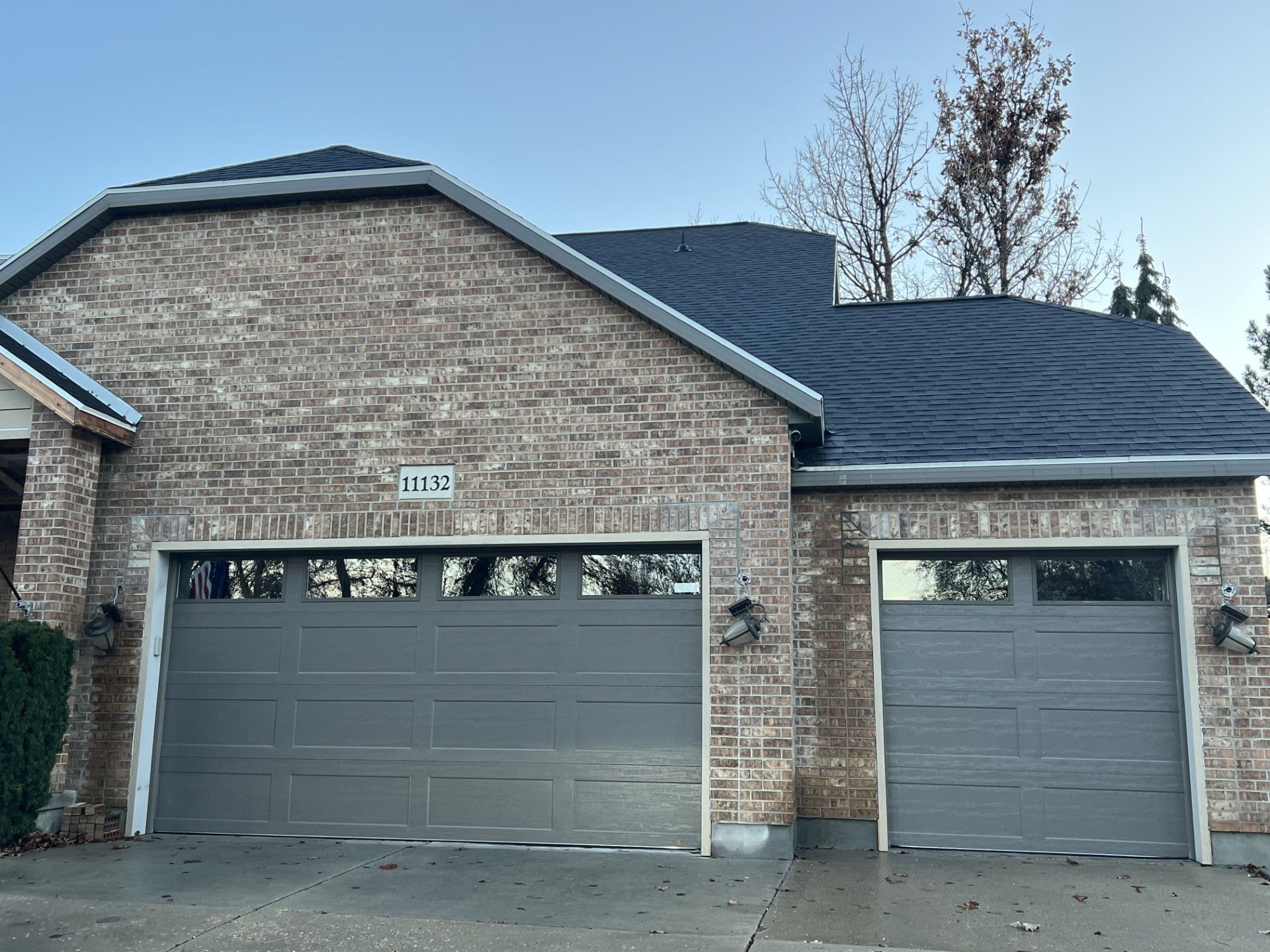 Tan brick house with gray garage doors and a dark roof.