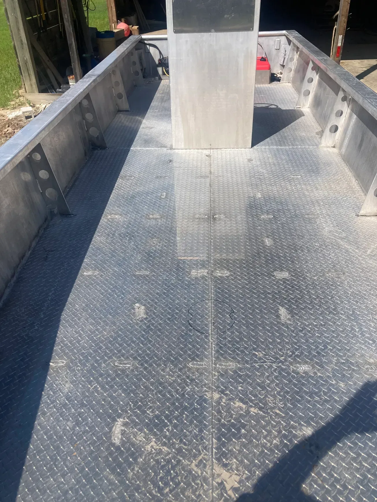 The floor of an aluminum boat with a diamond plate pattern, featuring a center console and side gunwales.