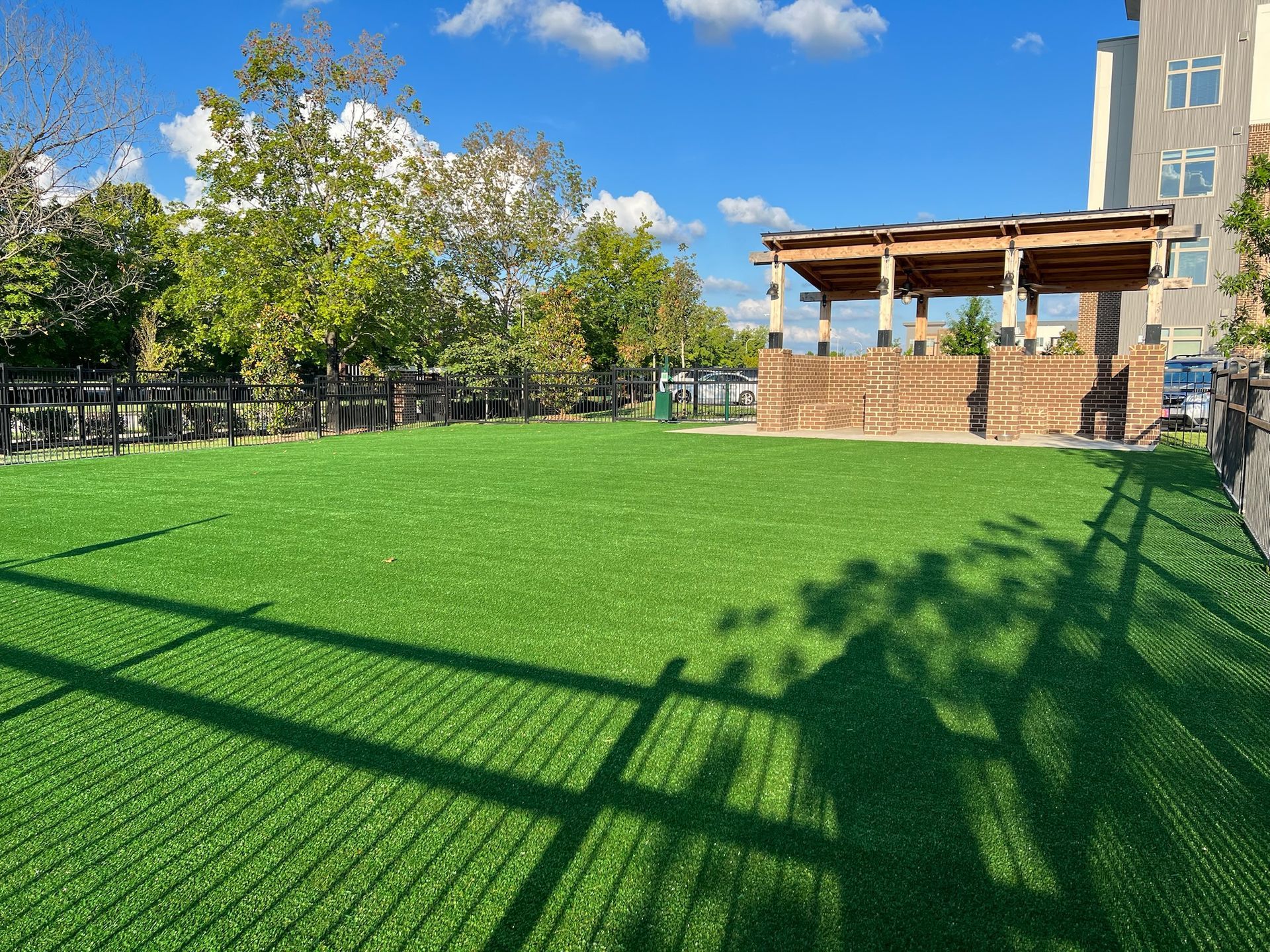 A large grassy field with a fence and a building in the background.
