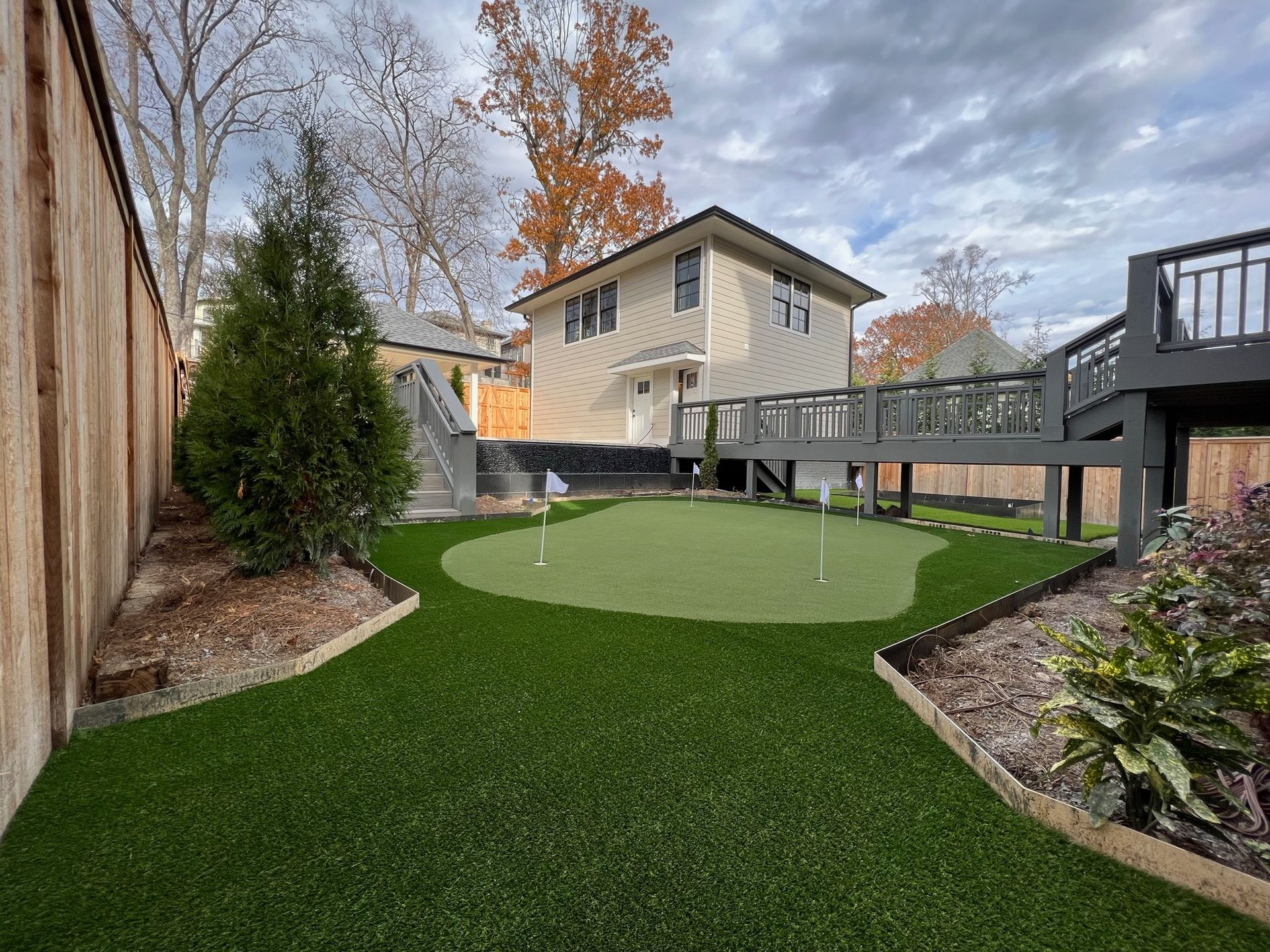 There is a putting green in the backyard of a house.
