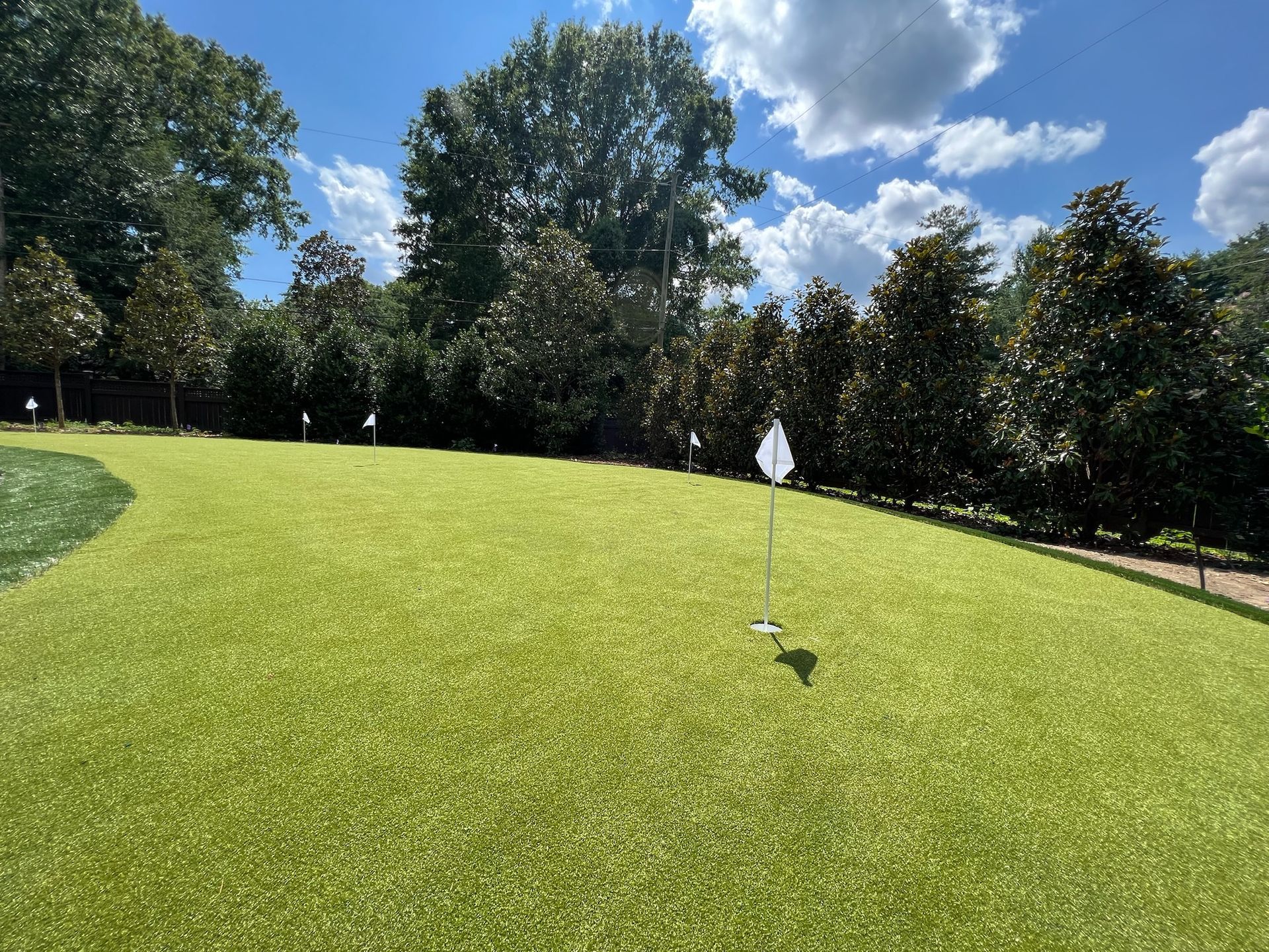 A golf course with a white flag on the green.