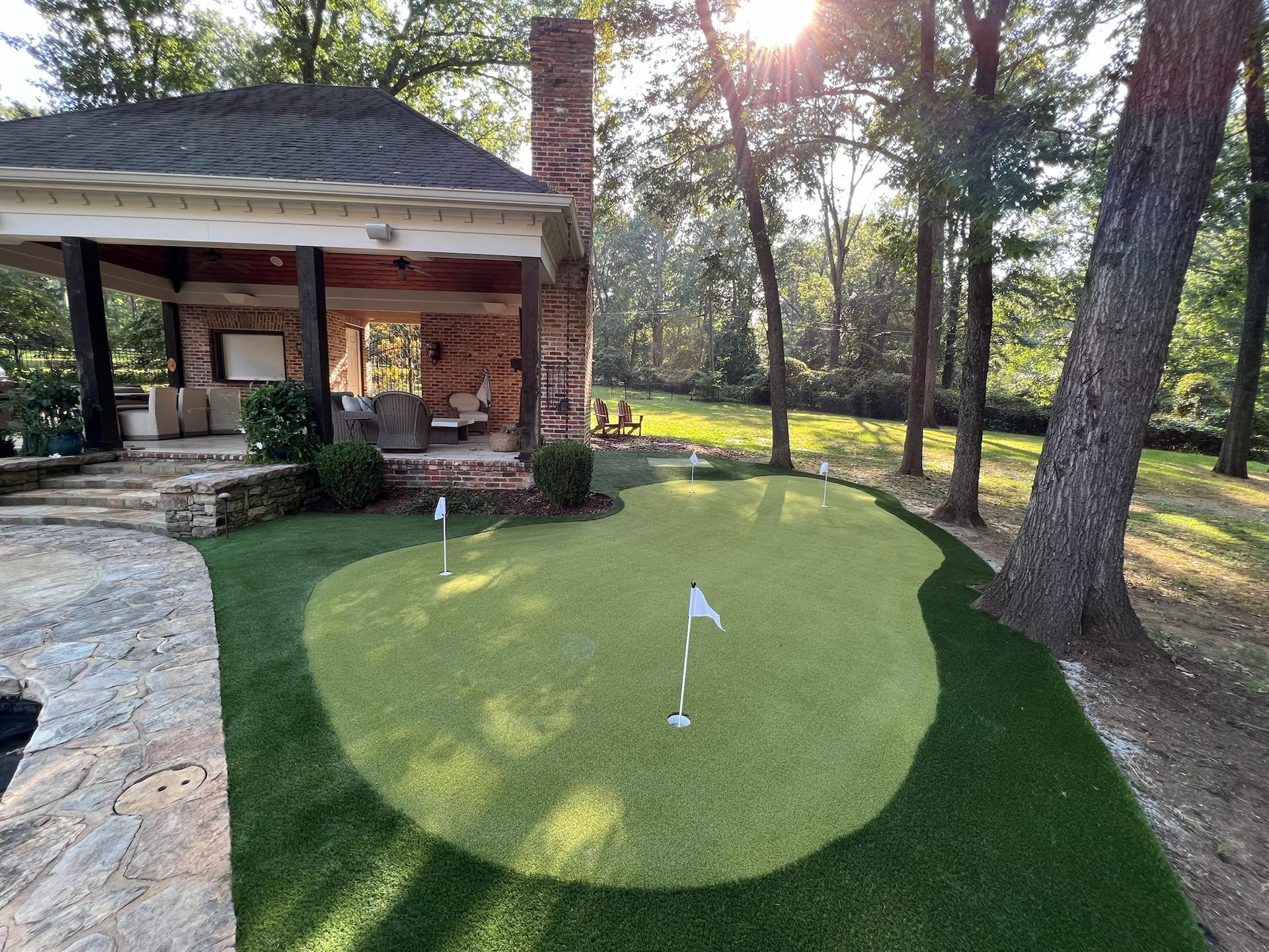 There is a putting green in the backyard of a house.