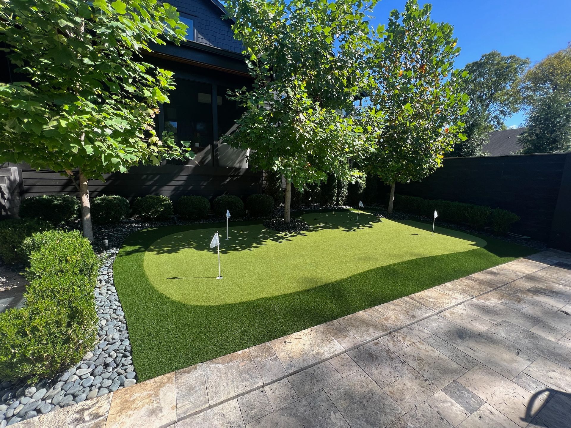 There is a putting green in the backyard of a house.